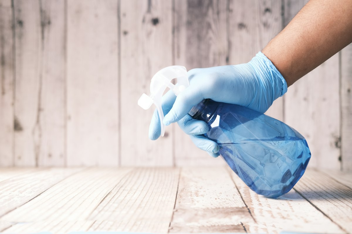 Gloved hand with a spray bottle over a freshly cleaned surface